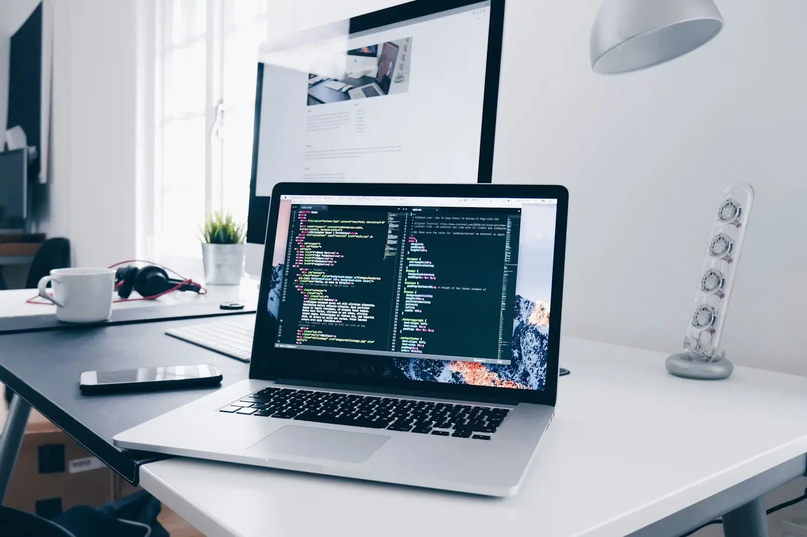Workspace with code on a monitor and notebook